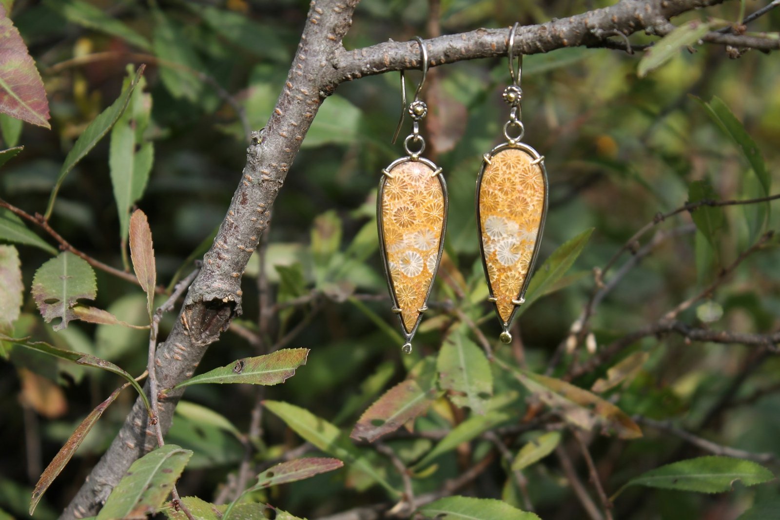 Boucles d’oreilles artisanales suspendues à une branche